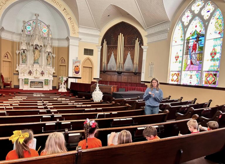 Photo of preschool kids at Lutheran Church of Our Redeemer. Church and teacher in background