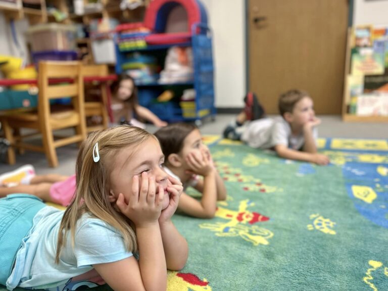 Photo of preschool kids laying down on rug for bible story time